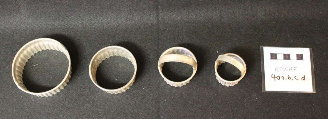 Four metal rings of varying sizes and a small white label arranged on a gray surface.