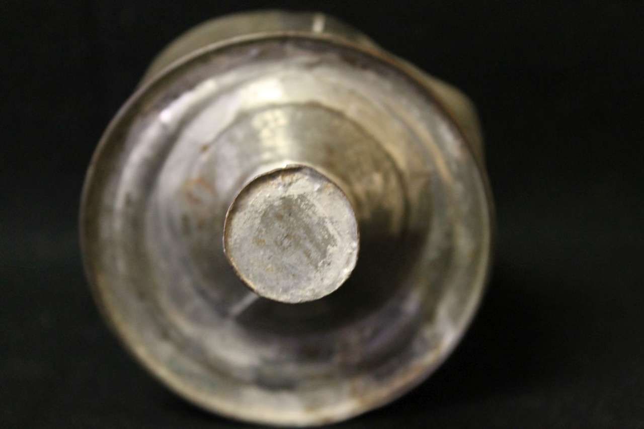 Close-up of a silver metal cylinder viewed from the open end against a black background