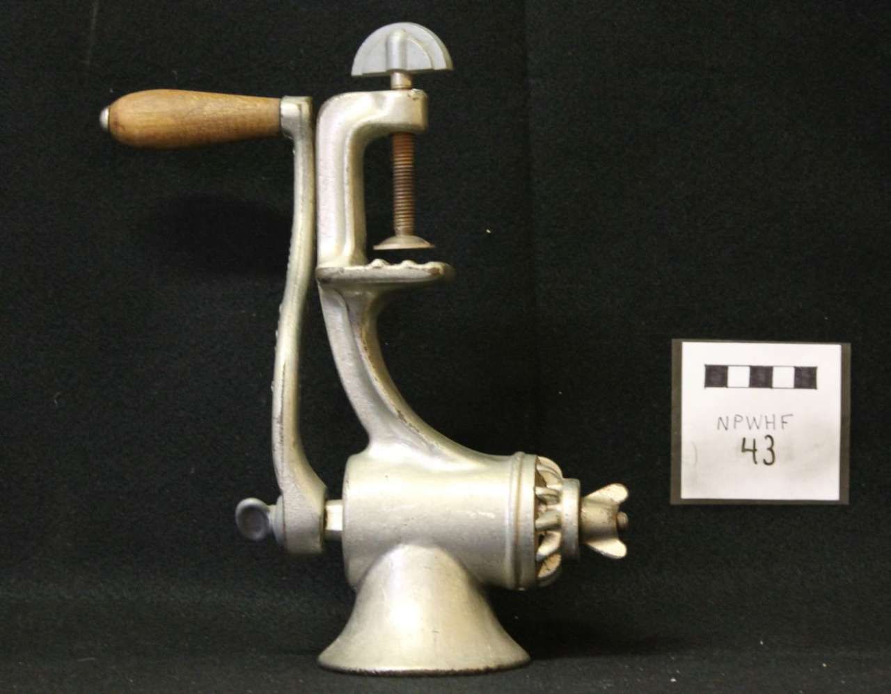 Vintage silver metal hand-crank kitchen grinder with wooden handle on a black background