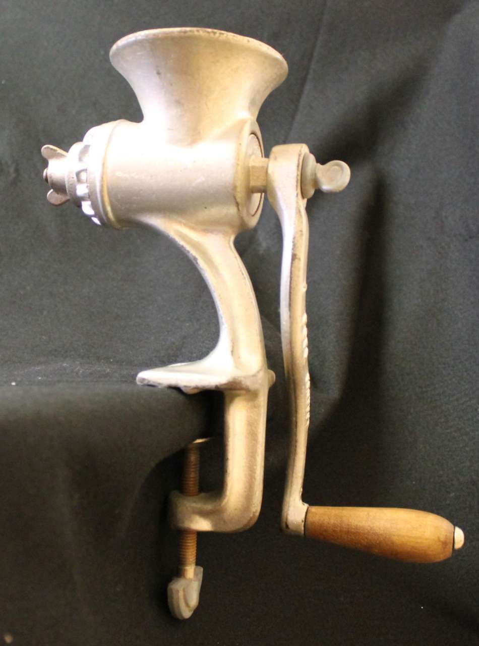 Vintage hand-crank meat grinder with wooden handle on a dark background