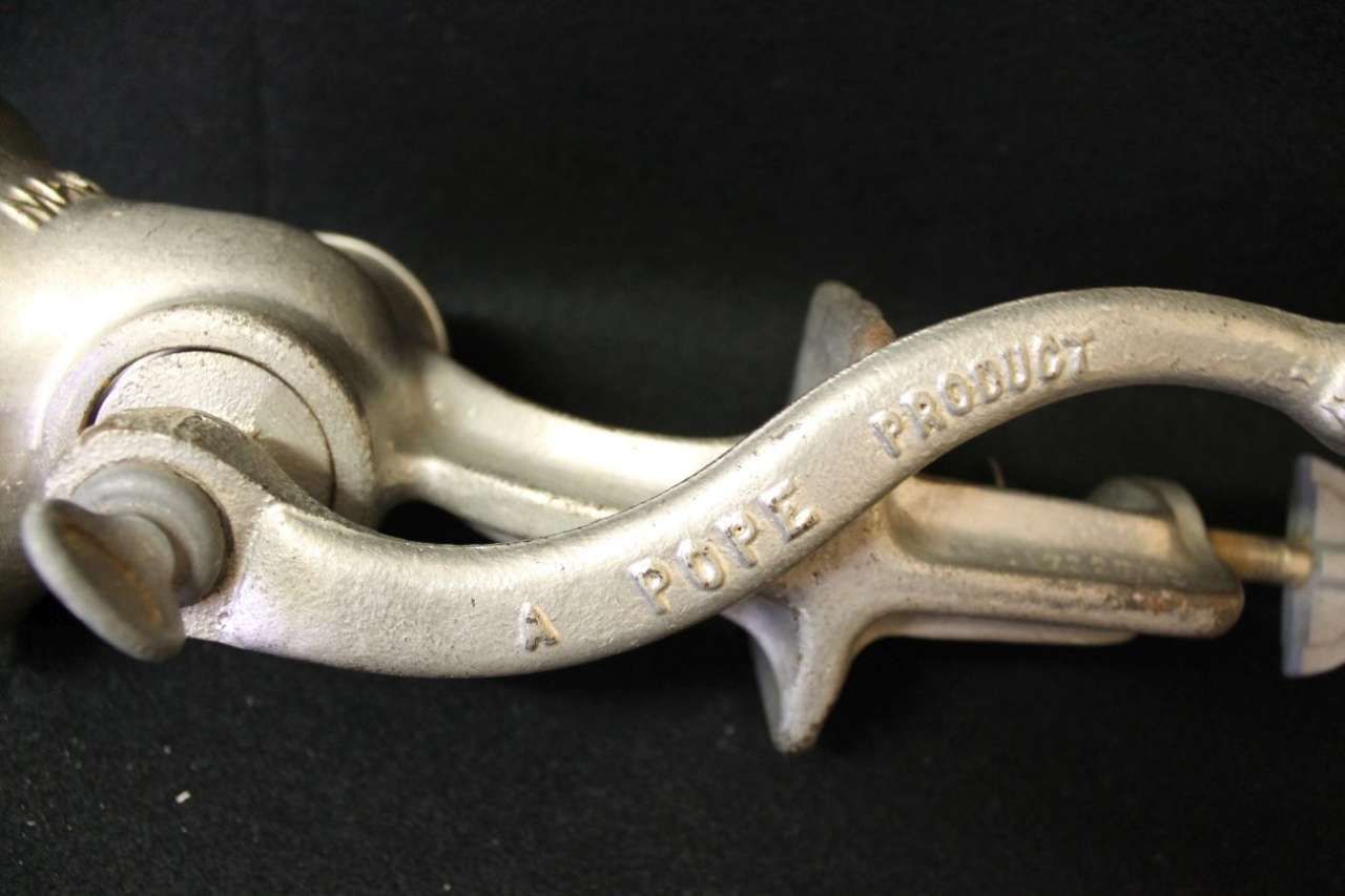 Close-up of a silver metal tool with curved handle and pointed tip on a dark background