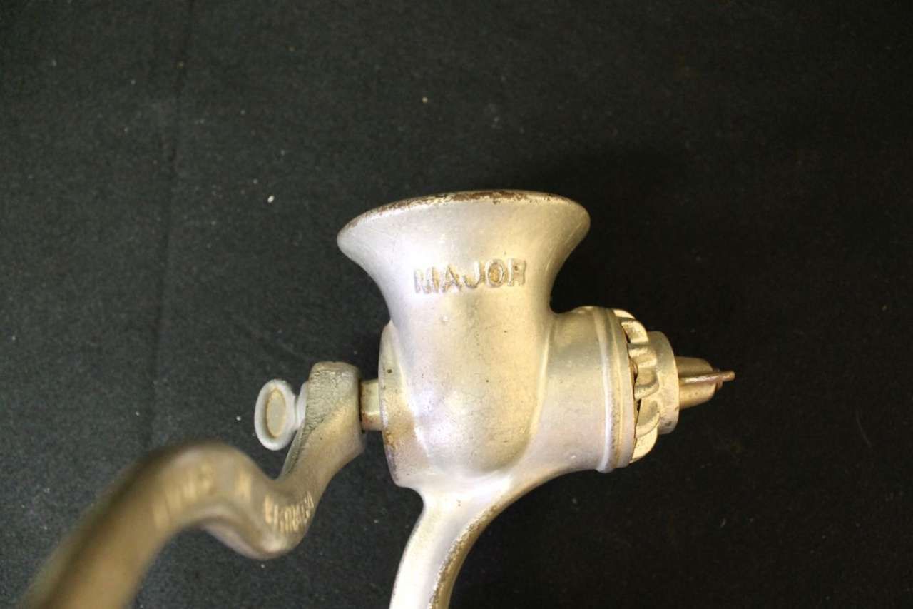 Close-up of a vintage metal hand-crank meat grinder on a dark background