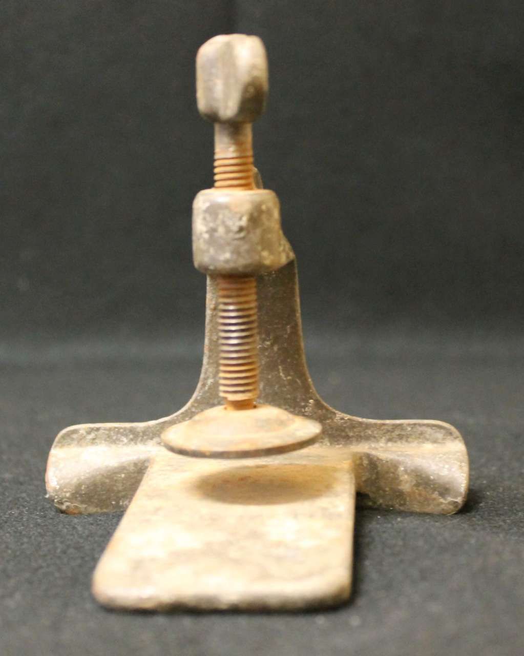 Rusty metal clamp with a threaded screw on a dark background
