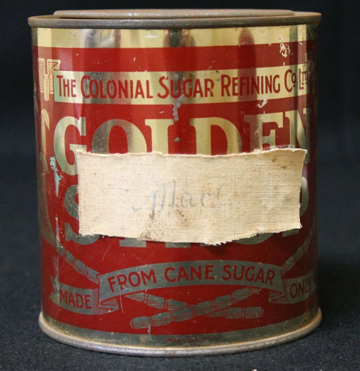 Vintage red and gold Colonial Sugar Refining Co. tin can with a faded paper label cover.