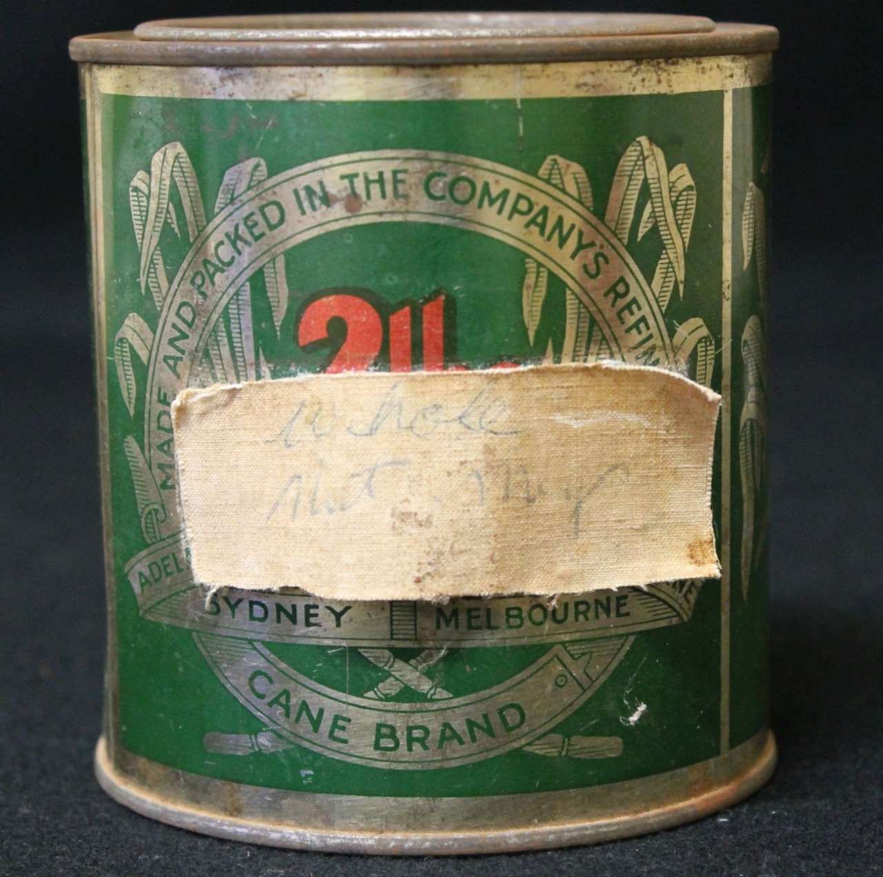 Vintage green cane brand tin can with a worn paper label and red “2” logo, showing signs of age and use