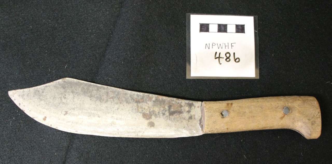 Large knife with wooden handle beside a small labeled evidence card on a dark surface
