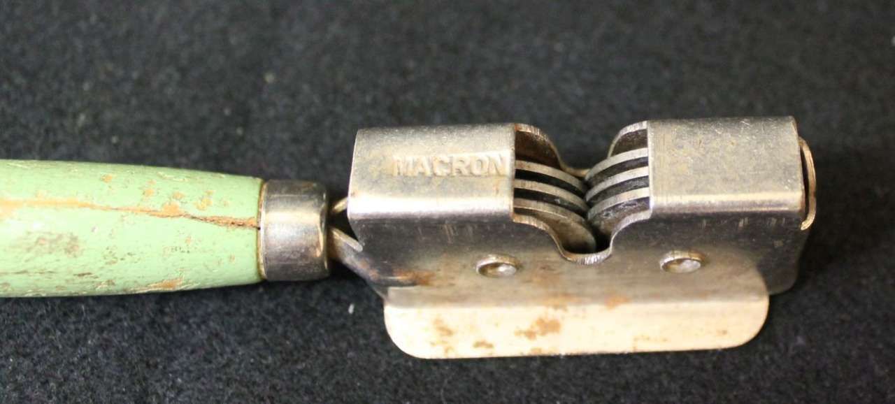 Close-up of a green-handled metal rasp with a black wavy filing surface on a white base.