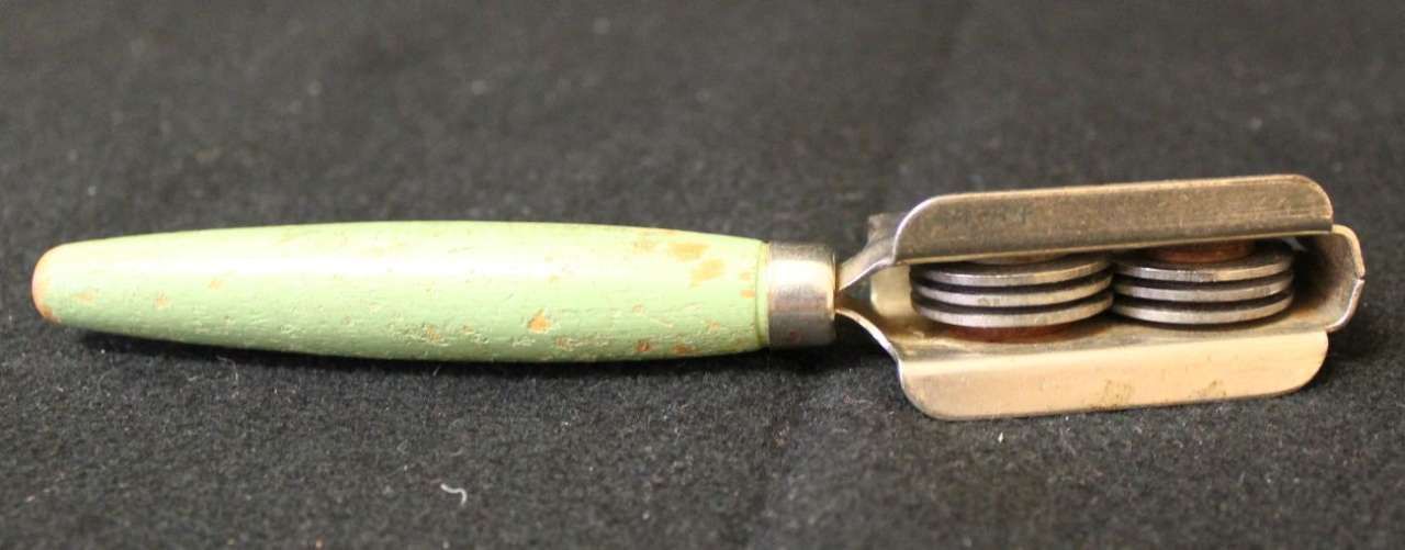 Green handled vintage hand-crank wafer press with stacked round wafers inside