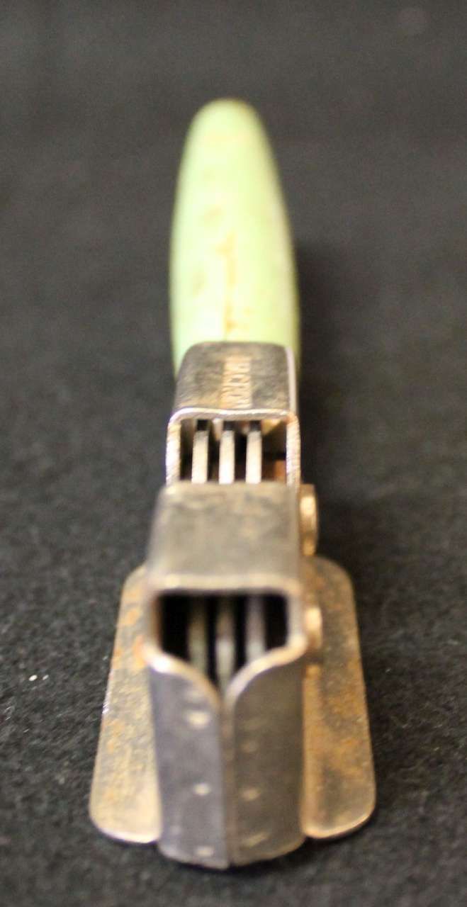 Close-up of a metallic guitar slide with a pale green handle on a dark background