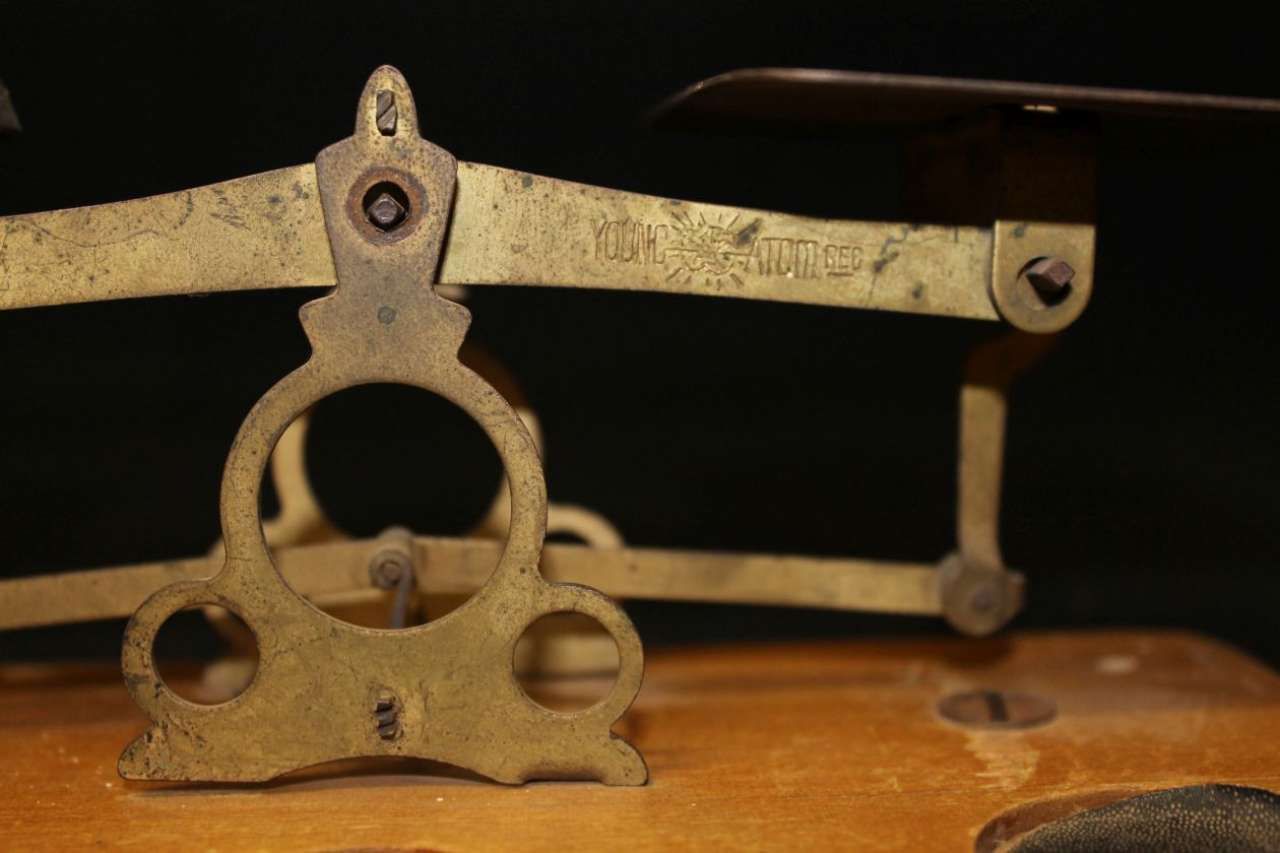 Brass mechanical tool with circular openings and articulated arms on a wooden surface