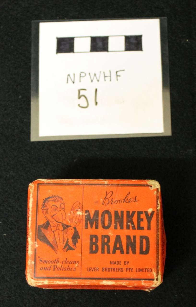 Two vintage tins: a white labeled box above and an orange “Monkey Brand” tin below.