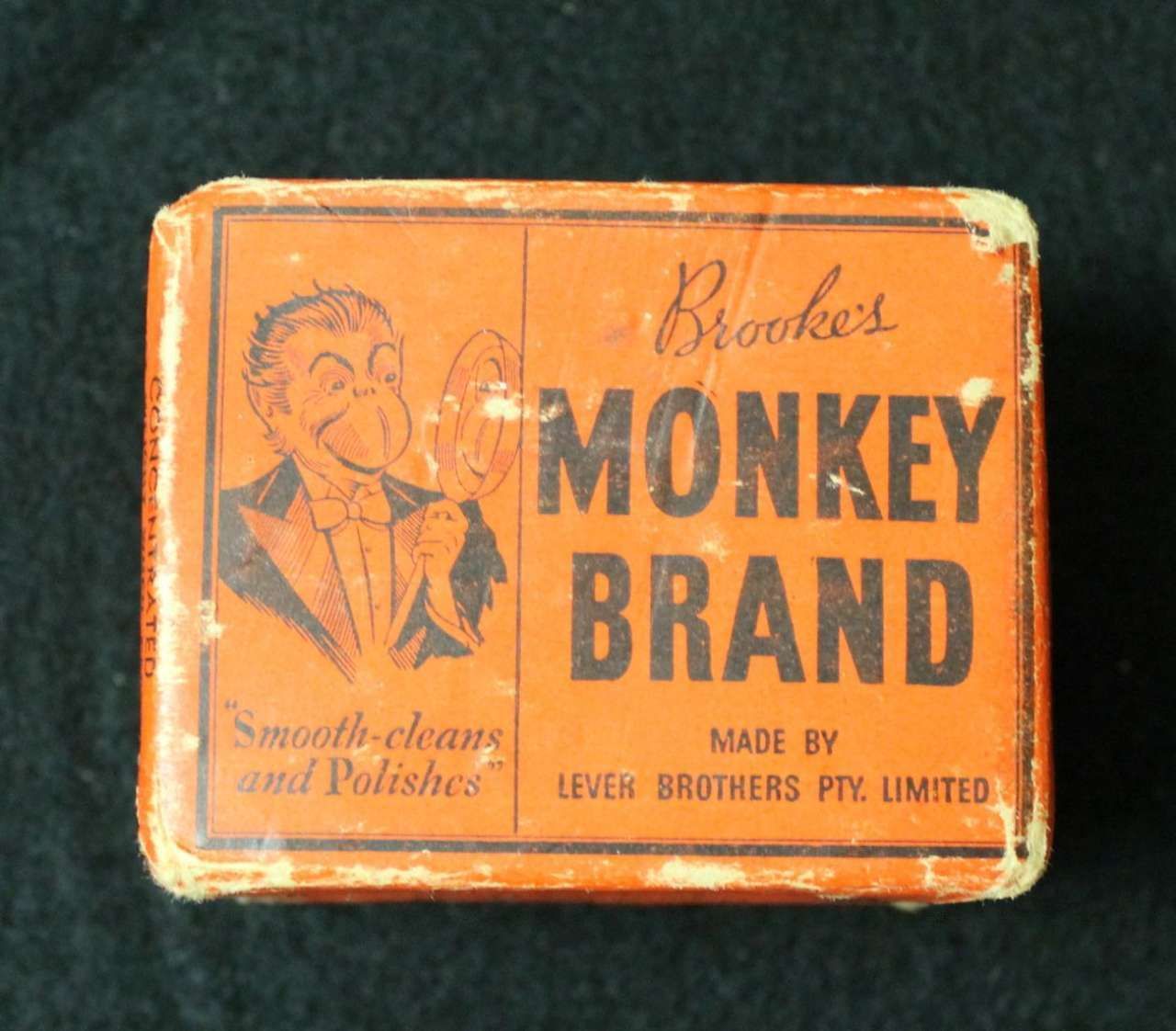 Orange vintage Monkey Brand soap tin with text and illustrated monkey logo
