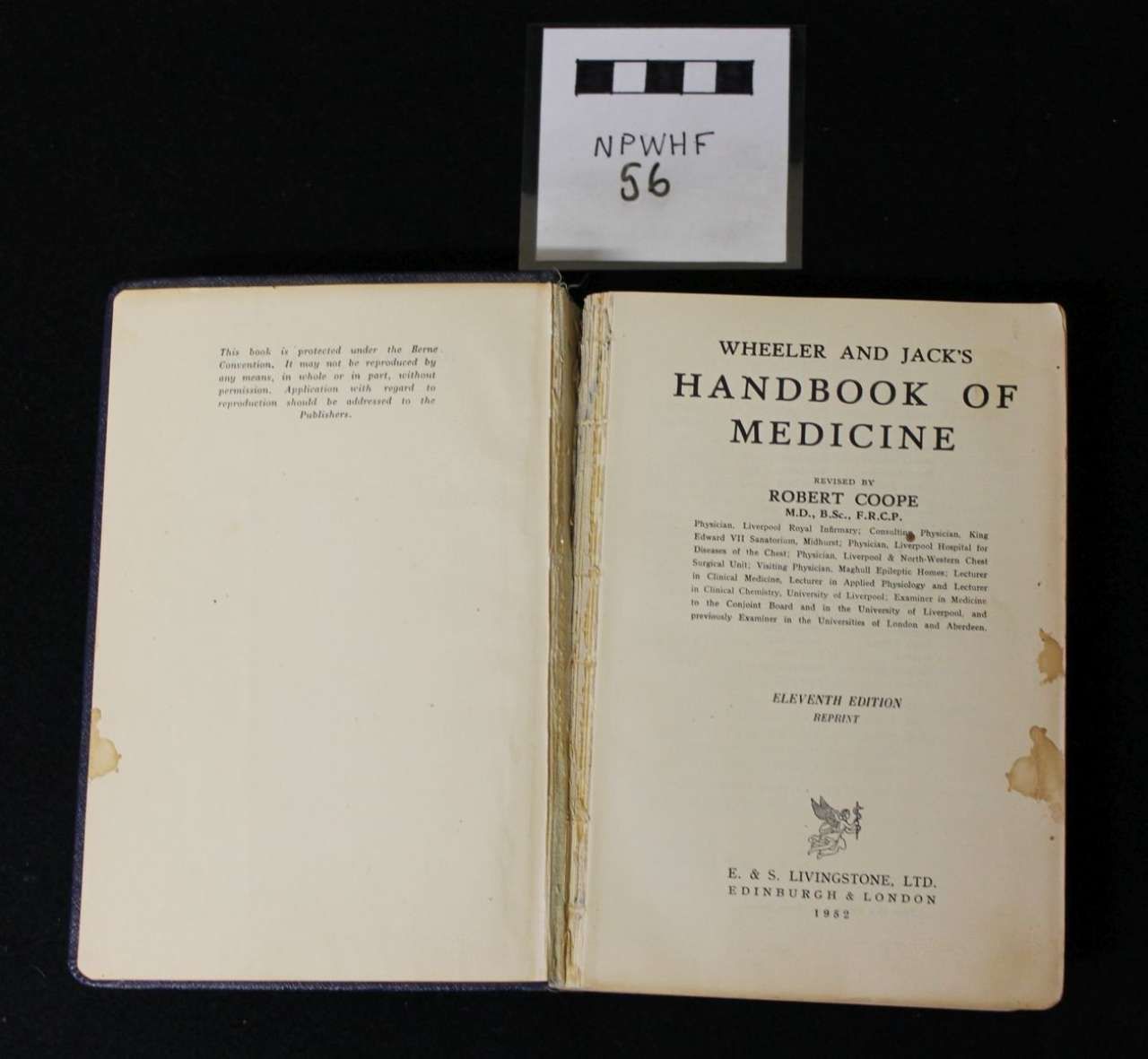 Open medical book titled “Handbook of Medicine” with a small labeled card above it on a black background