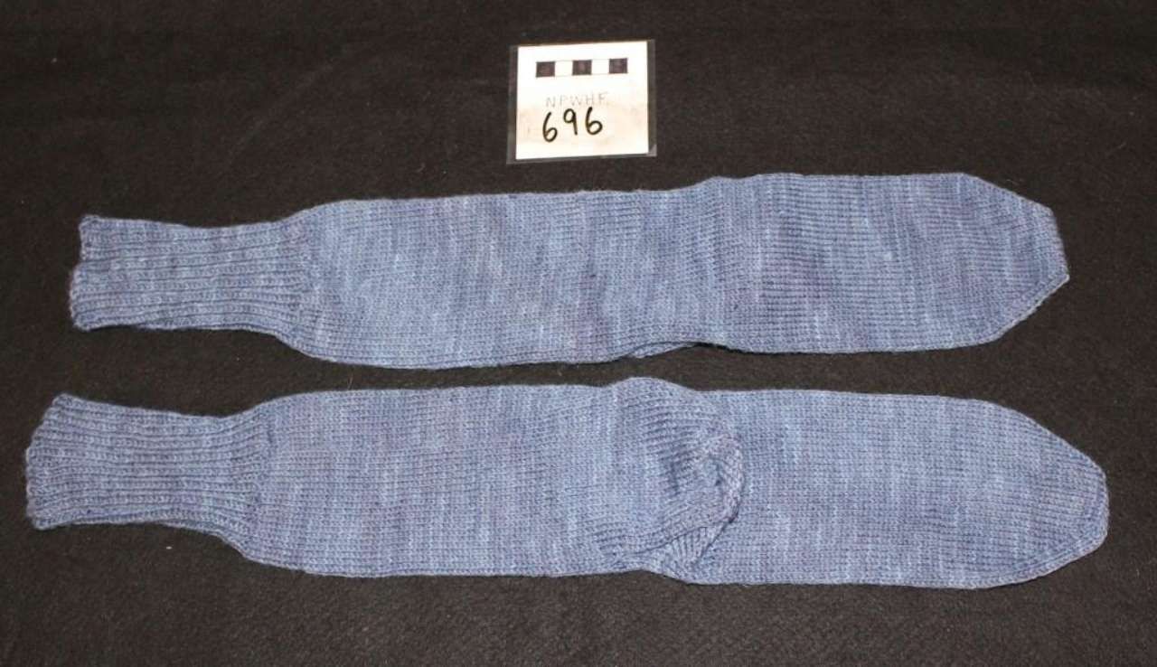 Two long blue patterned socks laid horizontally on a dark background with a small labeled card above.