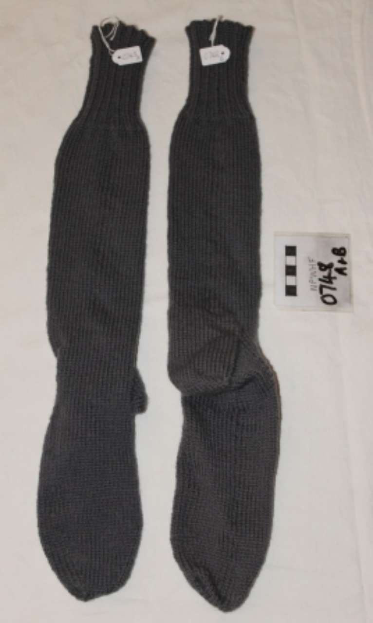 Pair of black socks laid side by side on a light surface, with small labels above and beside them.