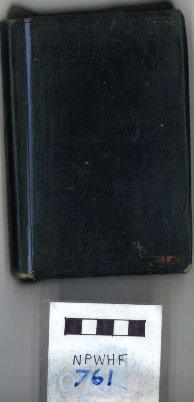 Black hardcover book above a small white label with handwritten text and a black-and-white scale bar