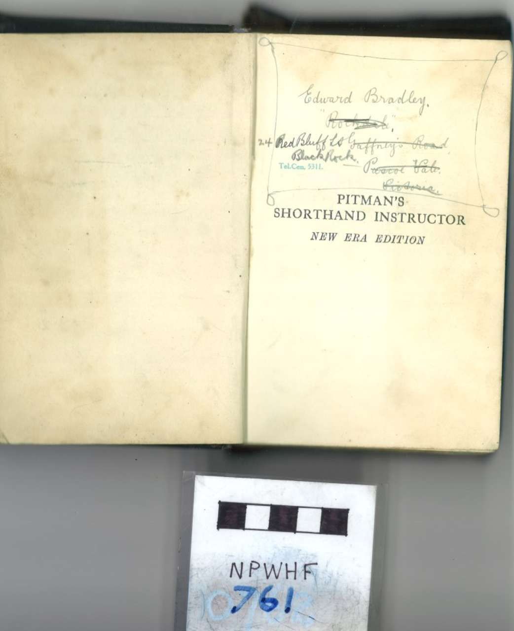 Open book with faded handwritten notes and title page; black-and-white label below.