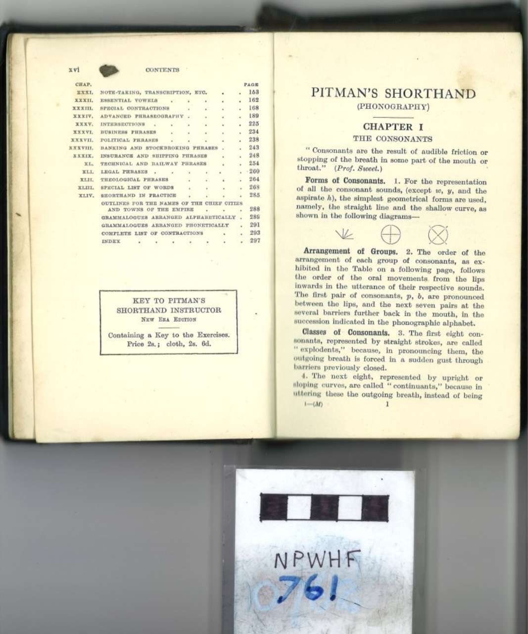 Open book with printed pages on a white surface, plus a small labeled card below.