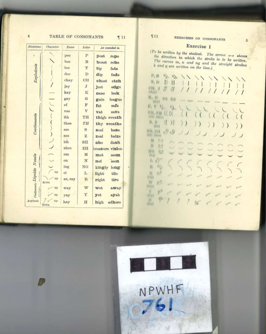 Open book with printed tables and musical notation, plus a small labeled card beneath it.