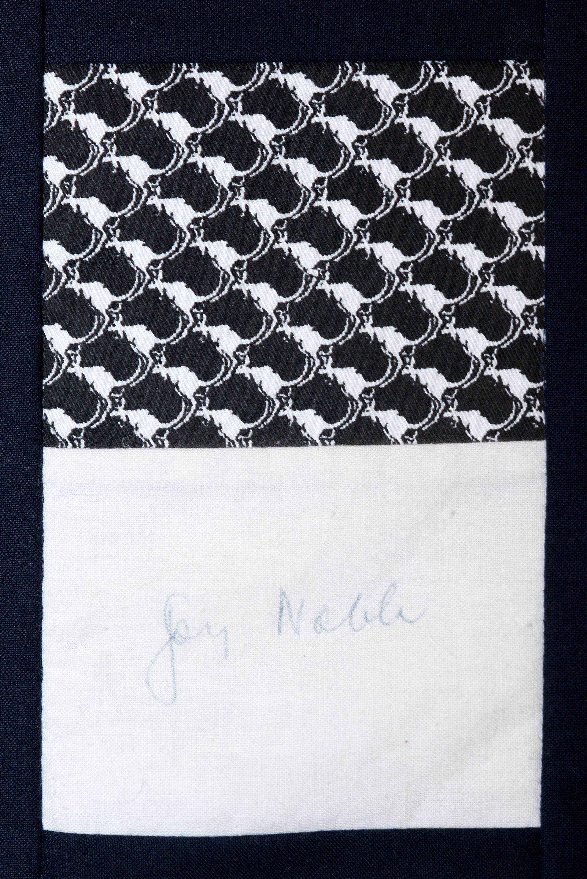 Black-and-white patterned fabric above a white label with faint handwritten text