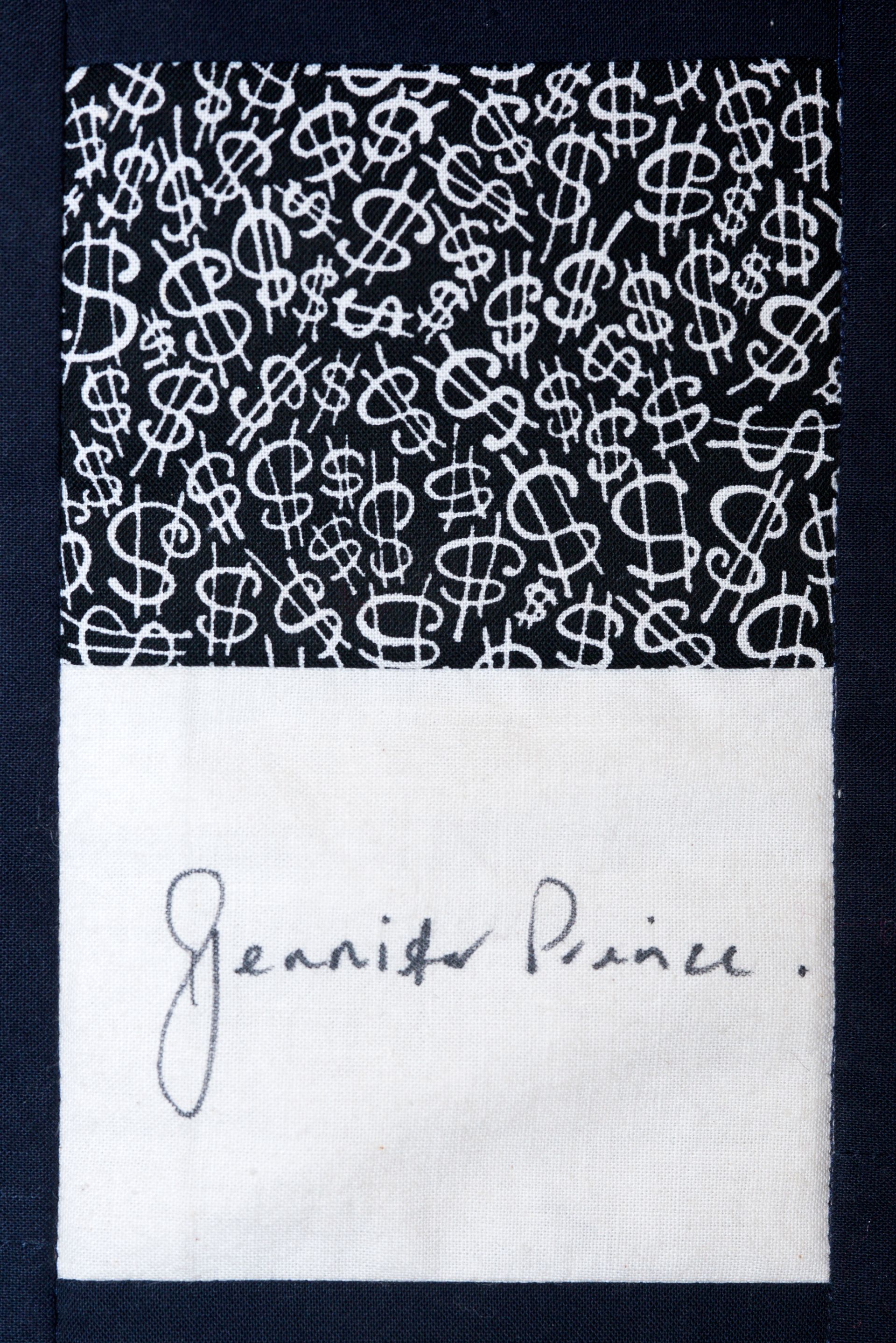 Black patterned fabric above a white cloth with a handwritten signature.