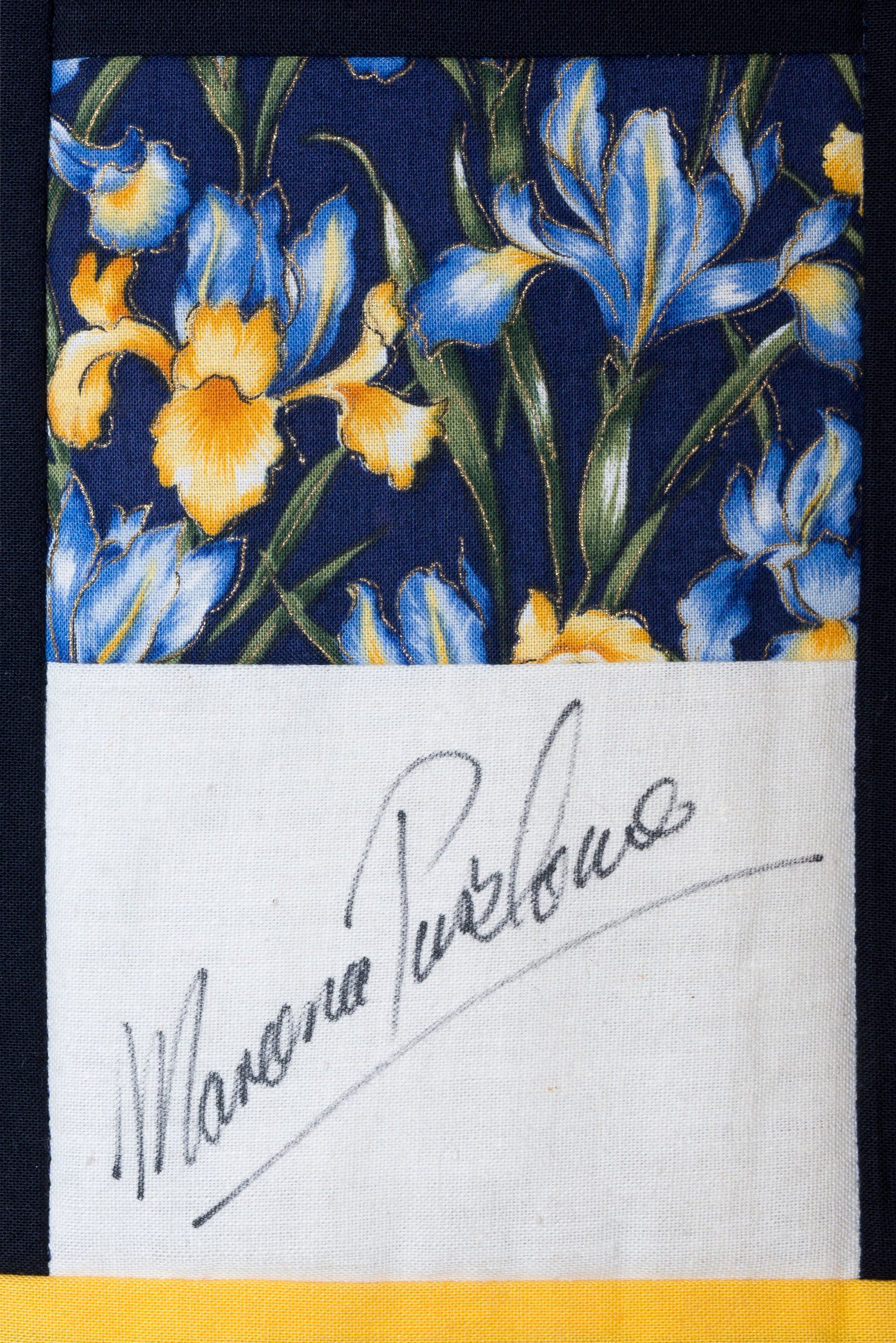Floral fabric with blue and yellow flowers above a white label signed in cursive