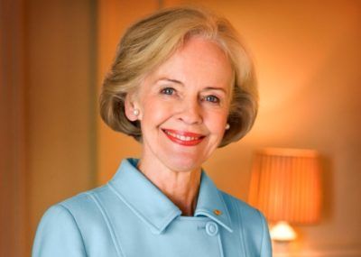 A woman in a blue coat is smiling for the camera.