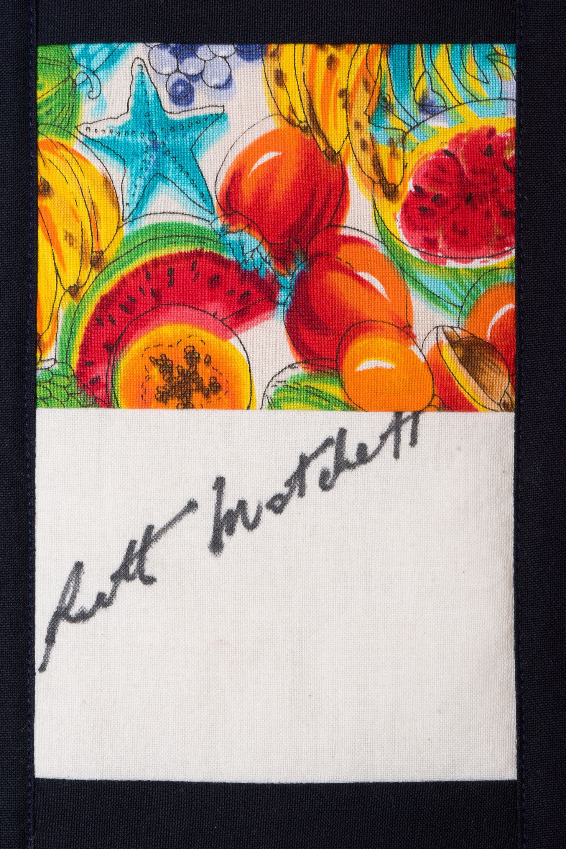 Colorful fruit painting above a white panel with a handwritten signature