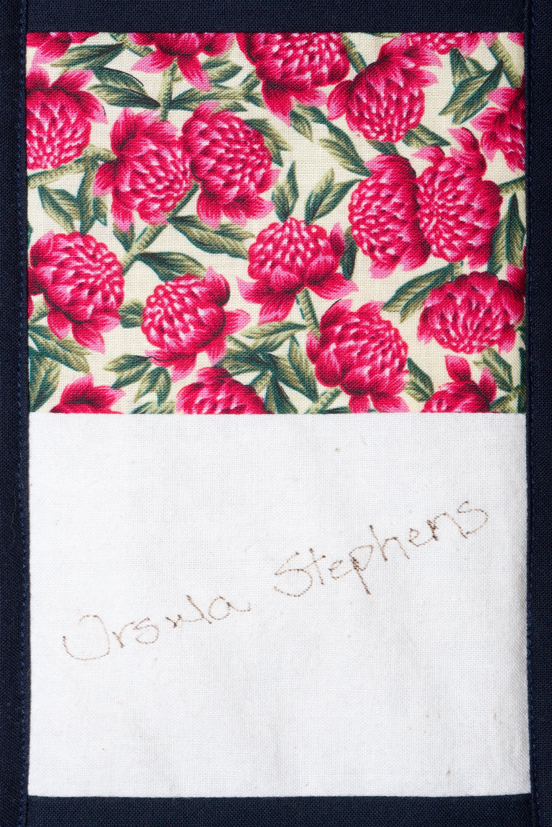 Floral red-and-green fabric above white cloth with faint handwritten text