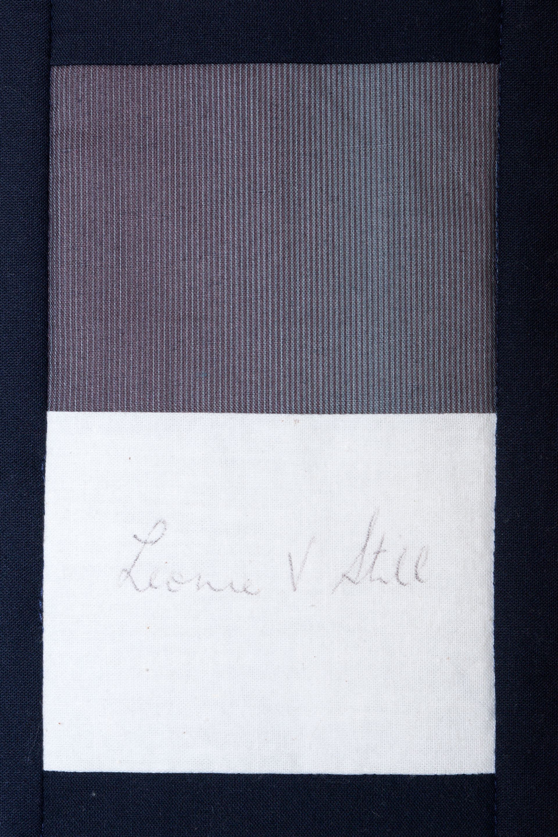 A small card with a gray top half and white bottom half, faintly handwritten with a name.