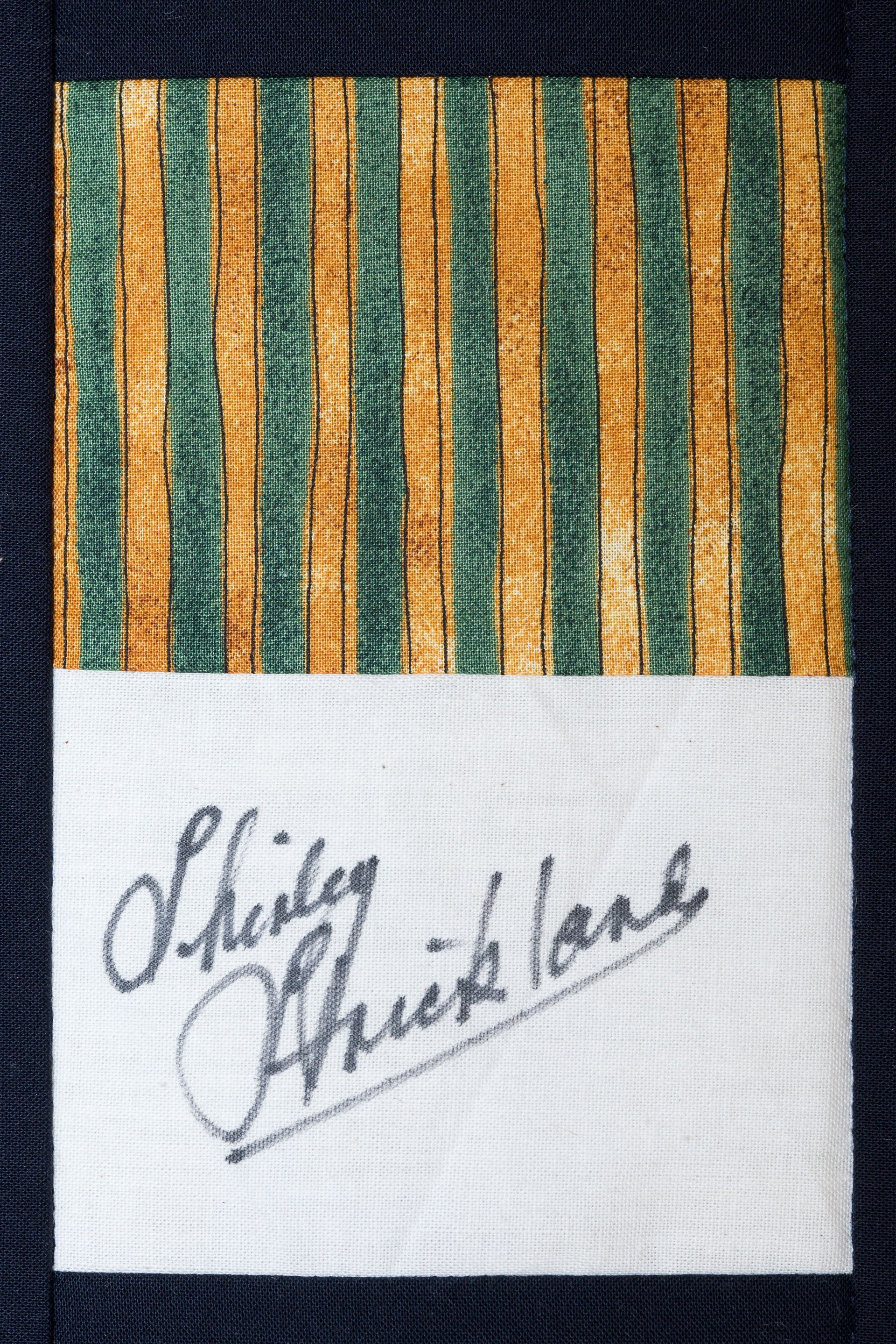 Striped fabric patch with handwritten signature on white paper label