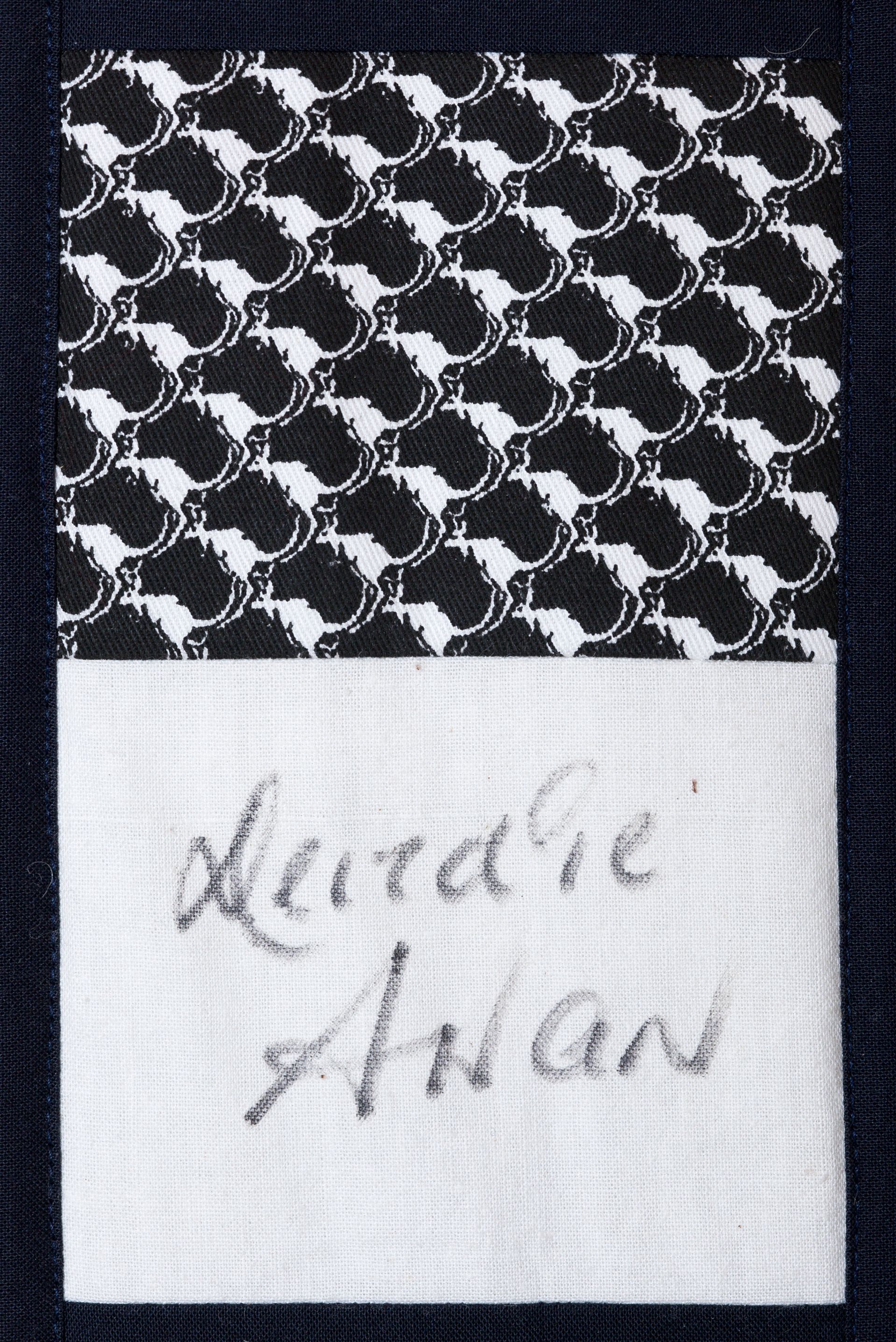 Black-and-white patterned fabric with a small handwritten note attached at the bottom.