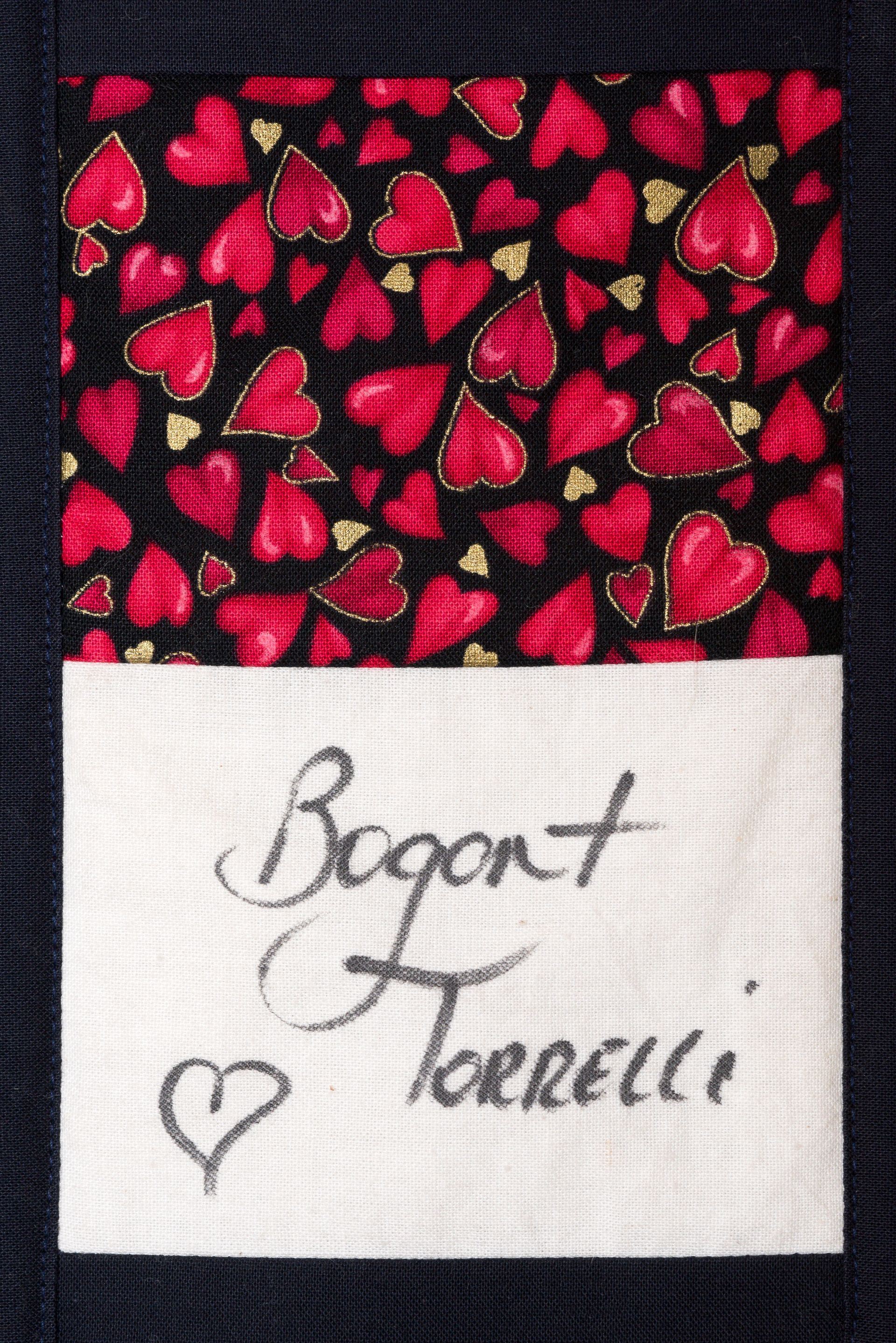 Black fabric with red heart pattern above a white label reading “Bogat Torrelli” with a small heart.