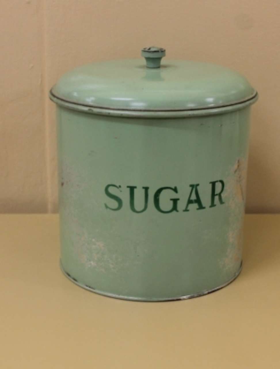 Pale green lidded sugar canister with the word “SUGAR” on the front.