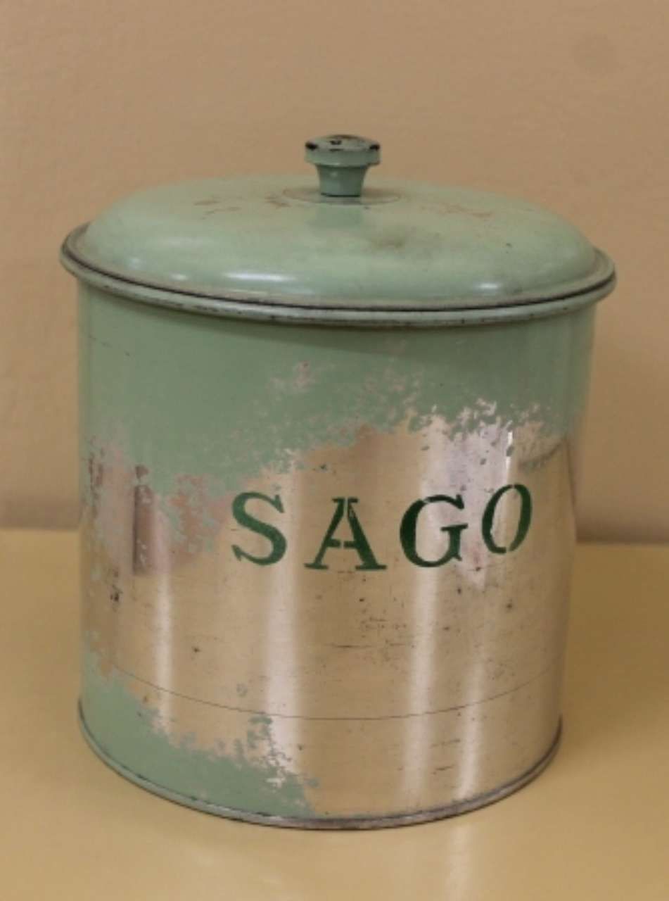 Vintage green tin canister labeled “SAGO” with a lid on a plain background
