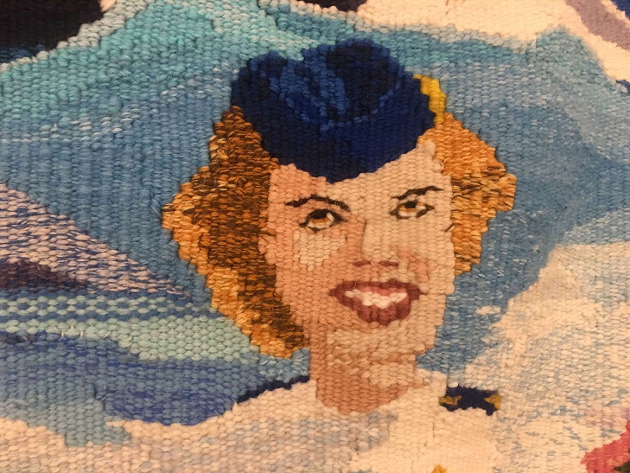 Smiling woman in a blue hat and white dress against a cloudy sky backdrop