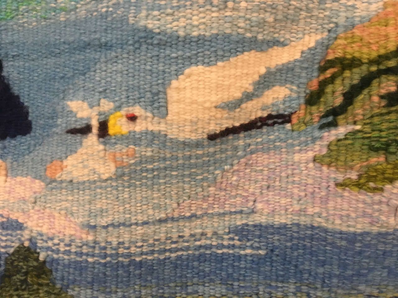 Beach scene with a white seagull flying over blue water and sandy shore beneath cloudy skies