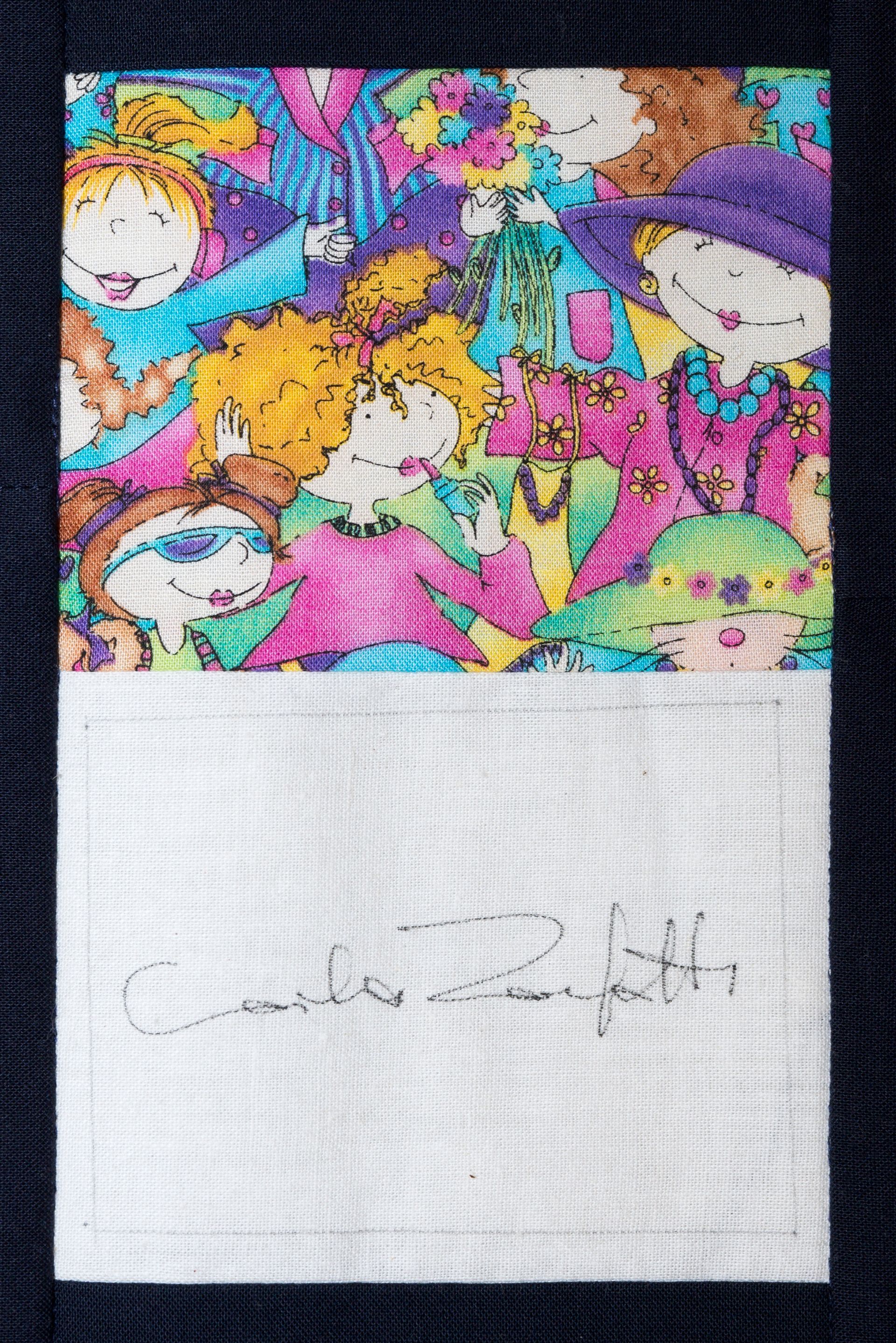 Colorful abstract collage above a white note with faint handwritten text on black fabric.