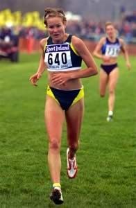 Runner in yellow shorts and bib 640 sprinting on a grassy racecourse, with another runner behind.