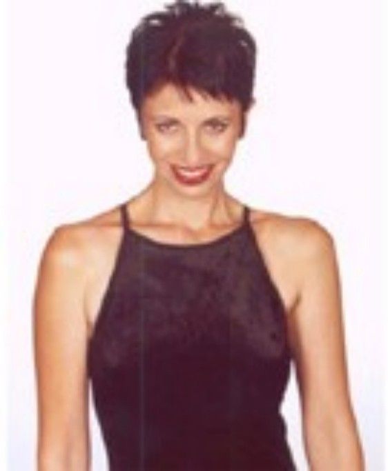 Person with short dark hair wearing a black sleeveless top, smiling against a plain white background