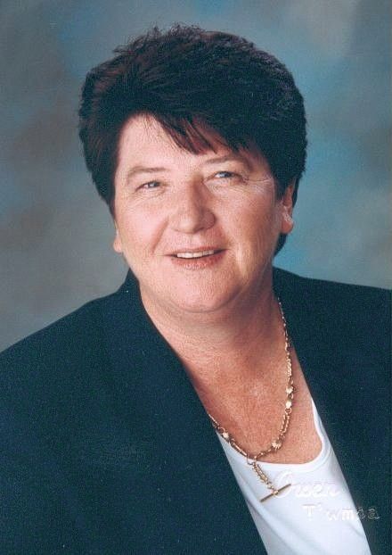Portrait of a smiling person in a dark blazer against a blue studio background