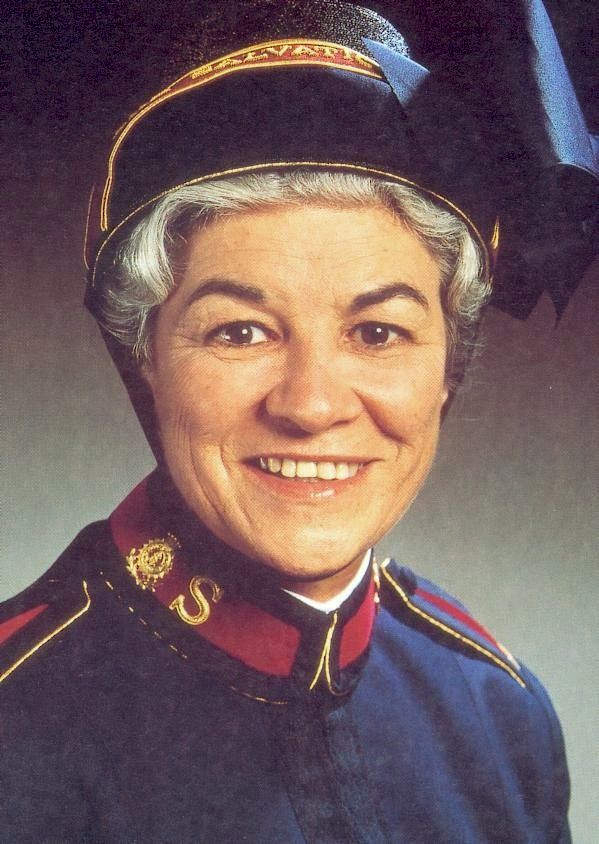 Portrait of a smiling uniformed person in a dark blue military-style jacket and cap