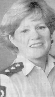 Smiling woman in a uniform shirt with epaulets, shown in a black-and-white portrait.