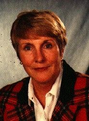Portrait of a person in a red plaid jacket and white shirt, facing forward against a gray background