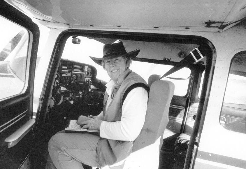 Man seated in a cockpit-style cabin, wearing a hat and looking toward the camera.