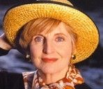Woman in a straw hat smiling at the camera against a dark background
