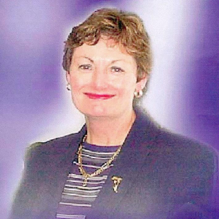 Portrait of a smiling woman in a dark blazer against a soft purple background