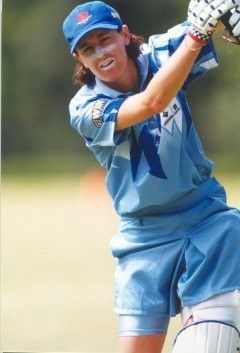 Cricket player in blue uniform swinging a bat during a match