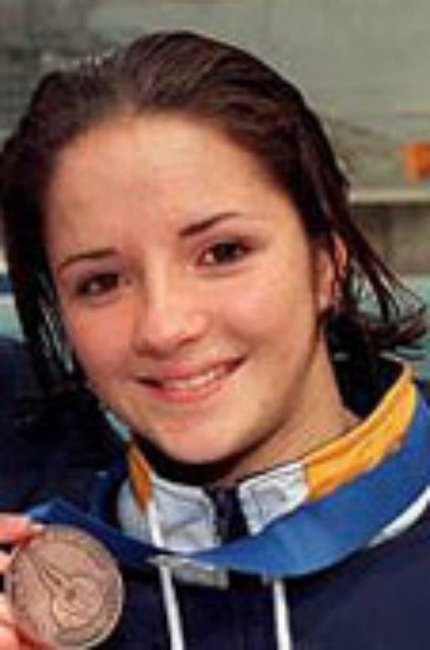 Smiling medal winner in blue jacket, close-up portrait with bronze medal visible