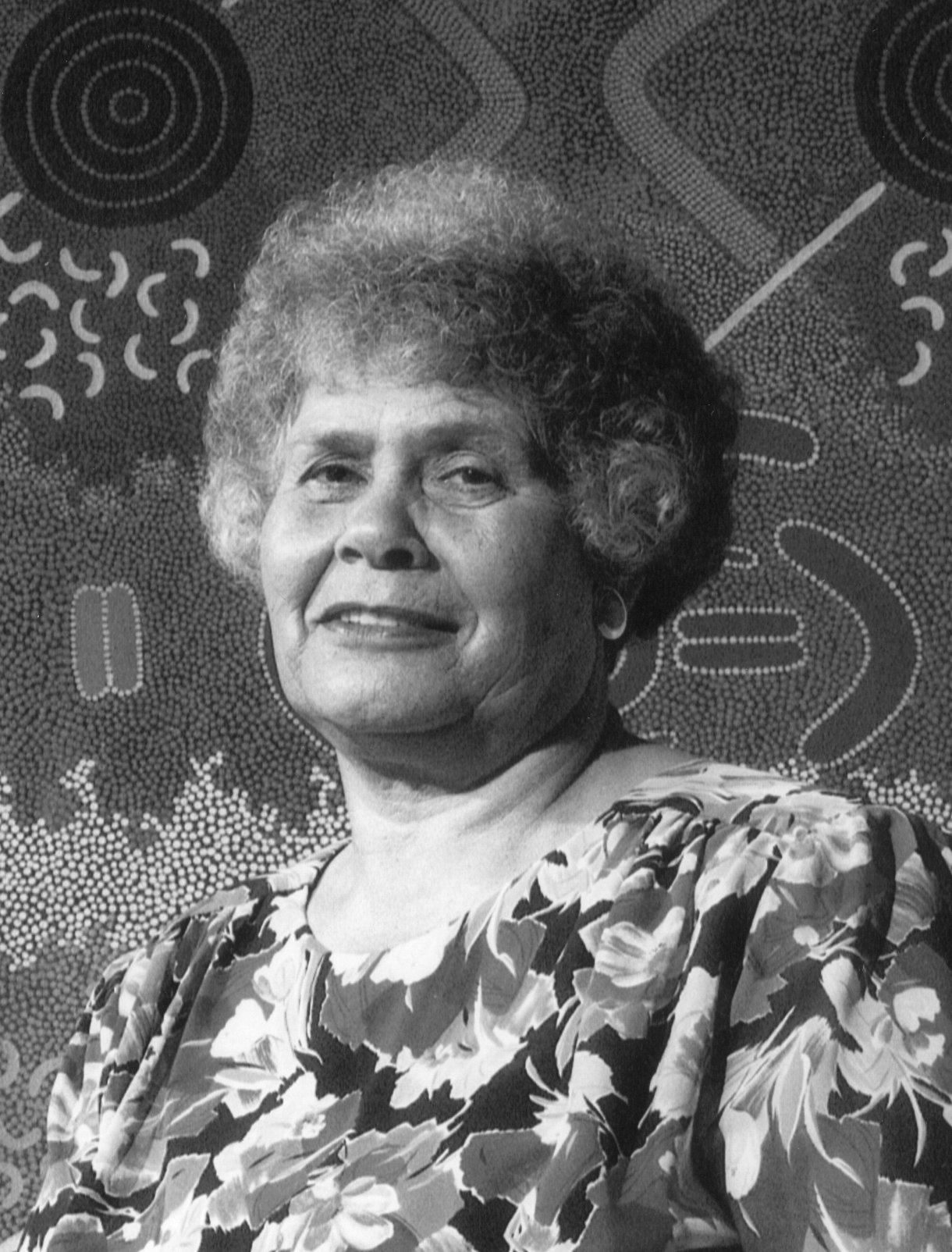Portrait of a woman in a floral blouse against a patterned background